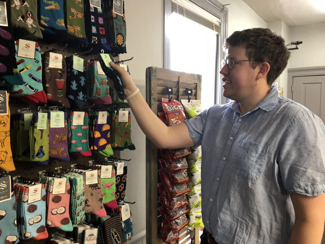 Jon Henry, owner of the eponymous Jon Henry General Store, stocks patterned socks on a wall display. Lewis Millholland/Daily